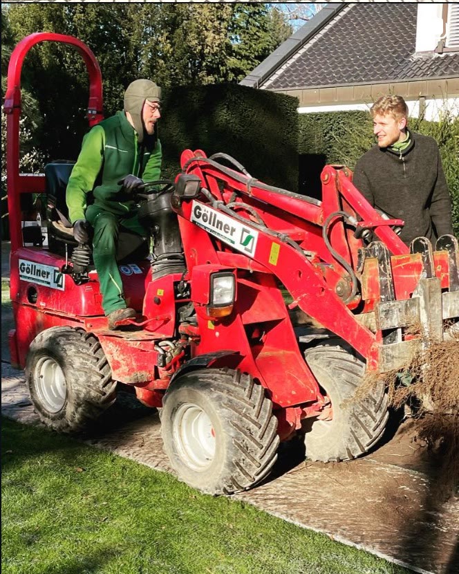 Zwei Mitarbeiter von Göllner arbeiten mit einem roten Radlader auf einer Baustelle